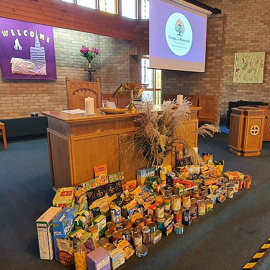 a picture of the communion table with a display of non-perishable foods in front of it.